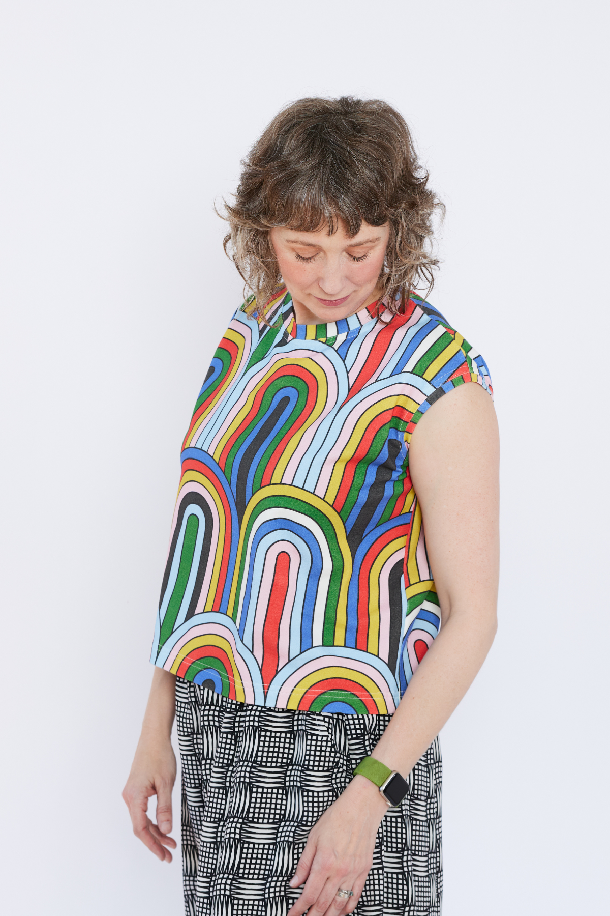 Person wearing a colorful rainbow-patterned shirt on a white background