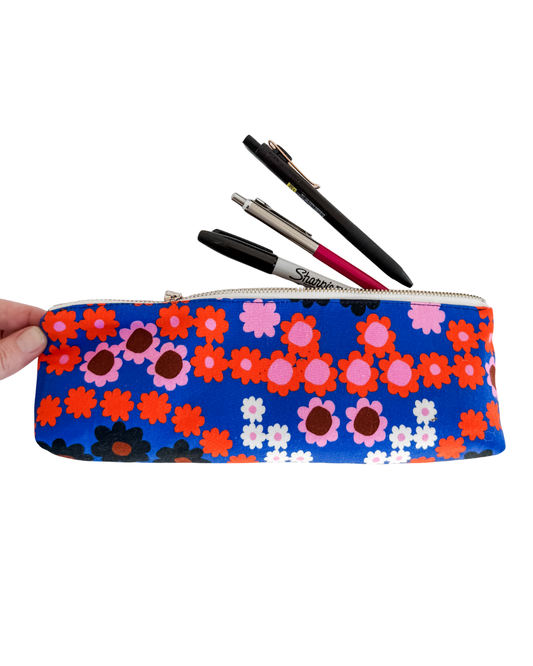 Floral-patterned pencil case with pens on a white background