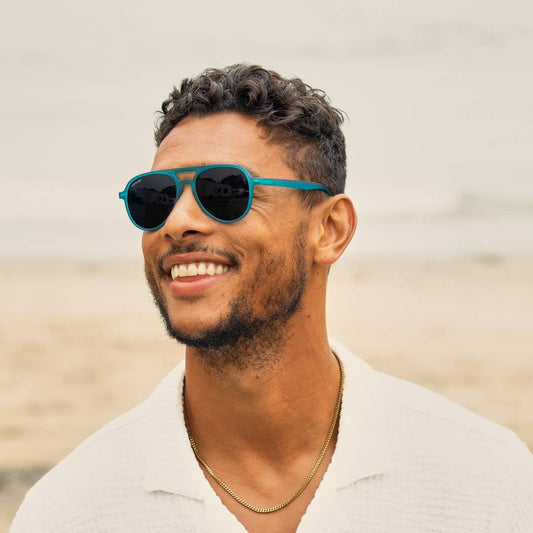 Man wearing teal sunglasses with a blurred background