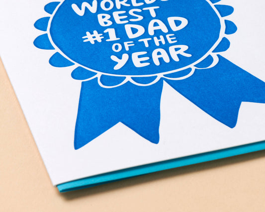 Card with blue ribbon design and text 'World Best #1 Dad of the Year' on a beige background