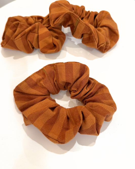 Two rust-colored scrunchies on a white background