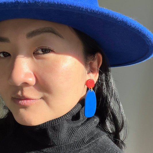 Person wearing a blue hat and colorful earrings with a blurred background