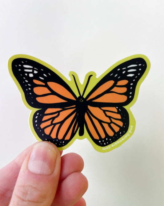 Butterfly-shaped sticker held by a hand against a white background