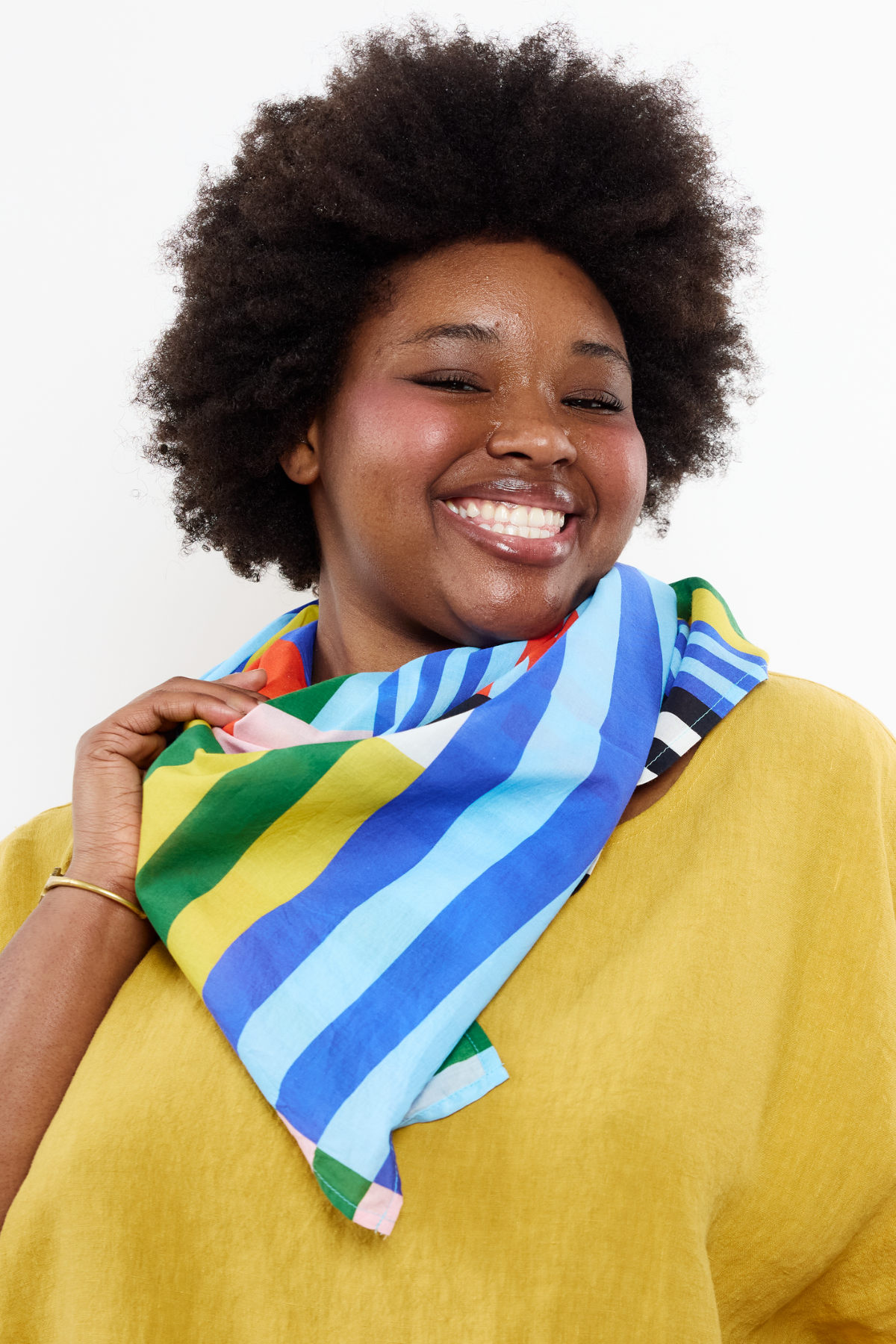woman wearing a chartreuse top and a colorful striped organic cotton scarf