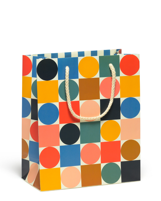 Colorful patterned gift bag with a white handle on a white background