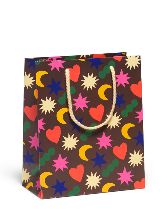 Colorful patterned gift bag with stars, hearts, and moons on a brown background.
