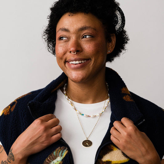 Woman wearing a dark blue jacket with colorful patterns, smiling against a plain background