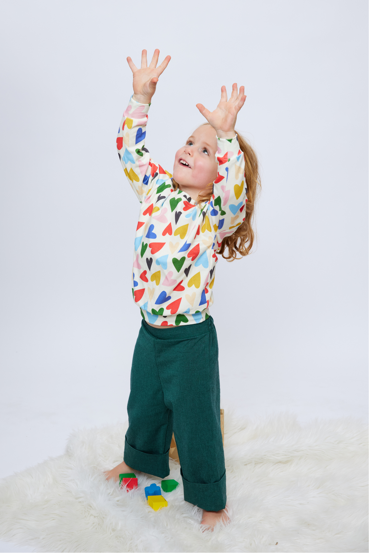 boy with long hair wearing an organic cotton top with colorful hearts