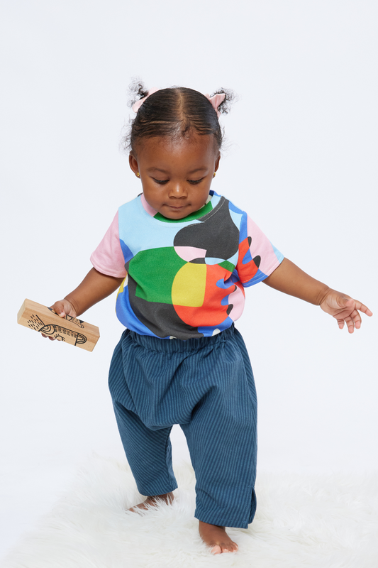 baby standing and holding a block while wearing gender neutral colorful clothing