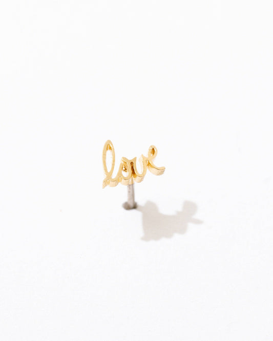 Gold 'love' stud earring on a white background