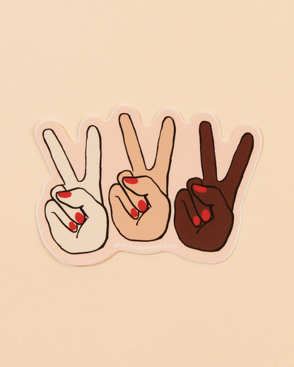 Three hands making peace signs in white, beige, and brown with red nail polish on a beige background.