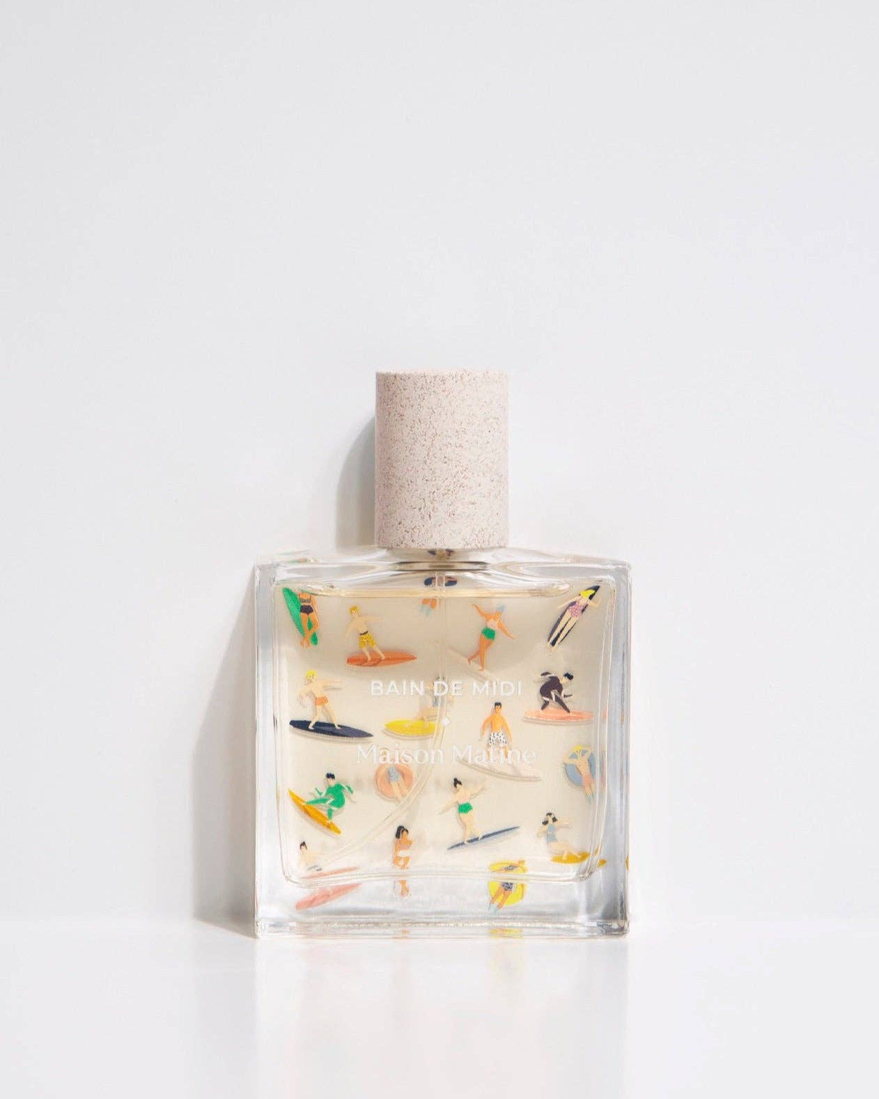 Glass bottle of eau de parfum titled Bain de Midi with colorful surfboard art.