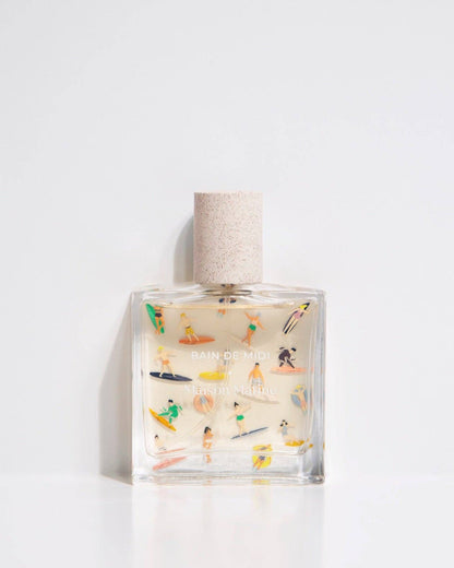 Glass bottle of eau de parfum titled Bain de Midi with colorful surfboard art.