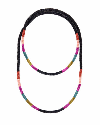 A beaded necklace with a black textured base and alternating colorful segments of pink, orange, teal, and olive green, shown on a plain white background.