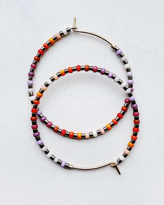 Colorful beaded hoop earrings on a light gray background