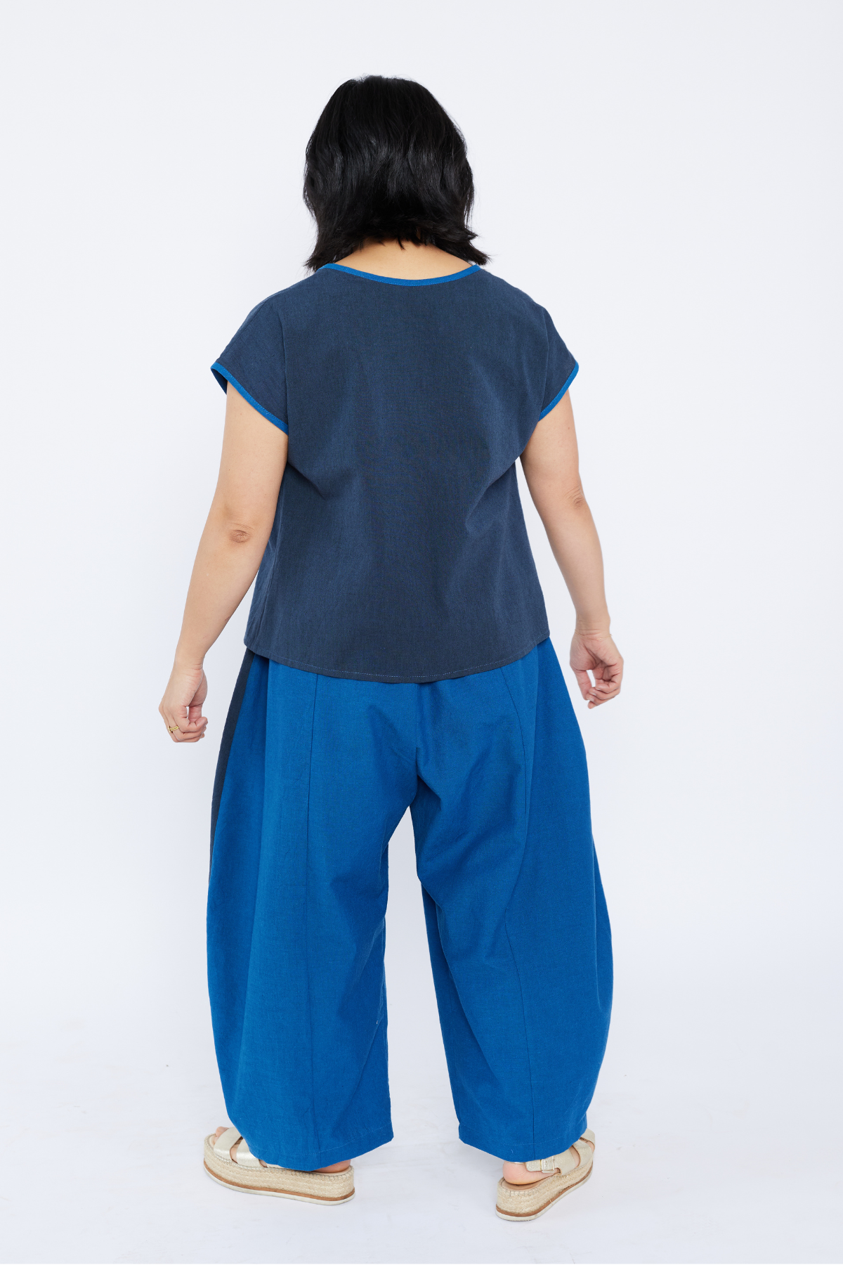 Person wearing a navy top and blue wide-leg pants on a white background