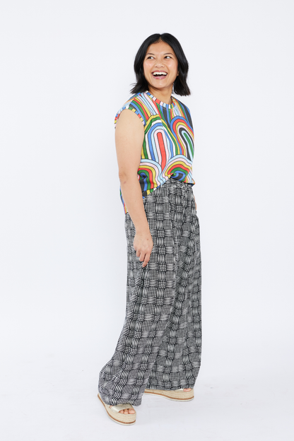 Woman wearing a colorful sleeveless top and patterned pants on a white background