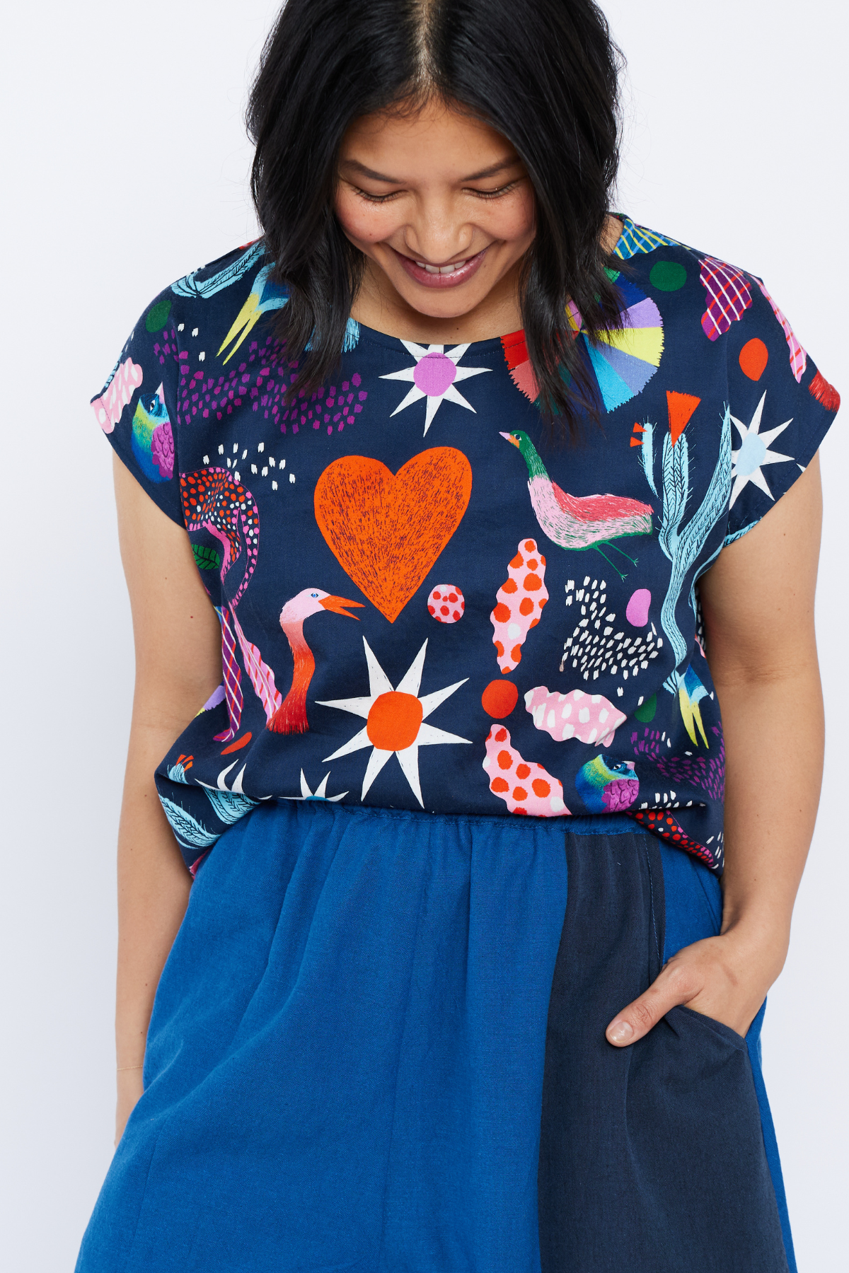 Woman wearing a colorful top with a heart design on a white background