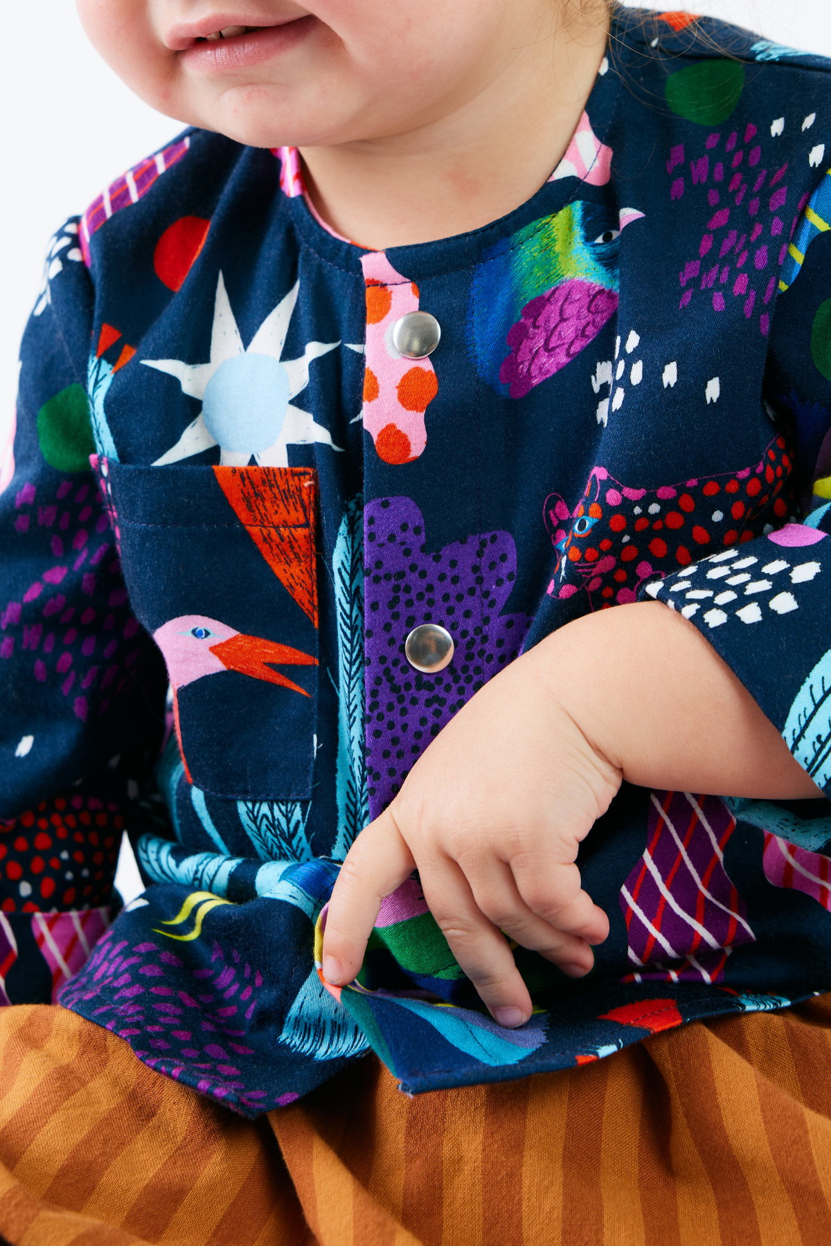 close up of a child wearing a colorful kid shirt with bright animals and plants.