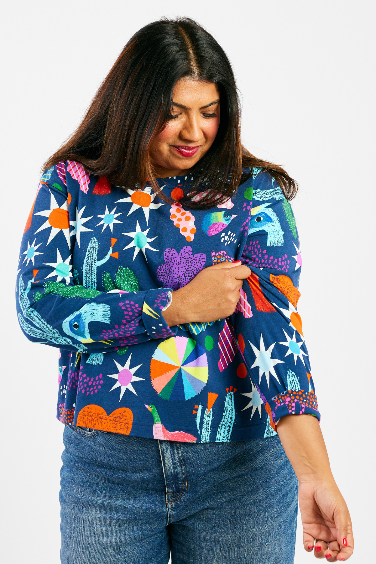 woman smiling and wearing a navy blue stretchy long-sleeve shirt with a colorful pattern. 