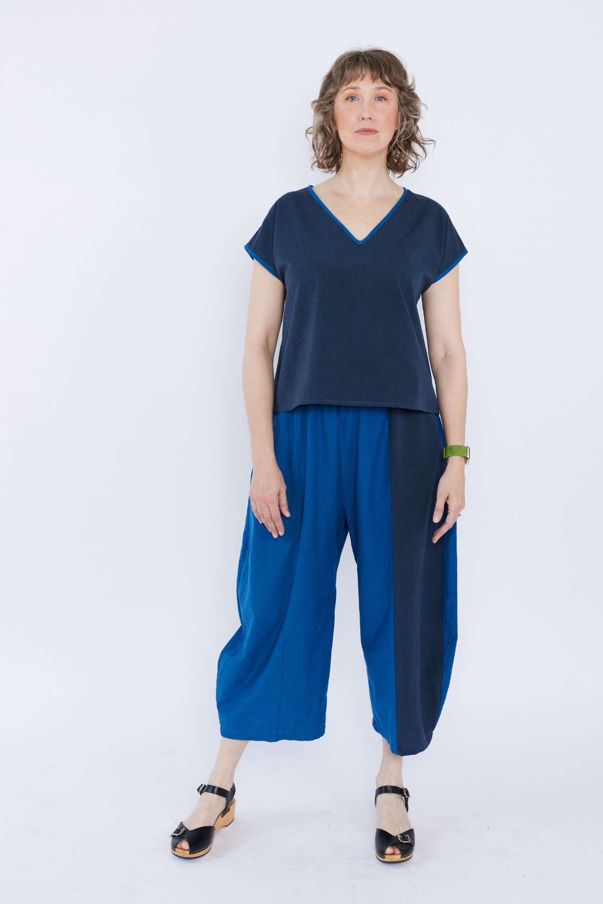 Woman wearing a blue top and wide-leg pants on a white background