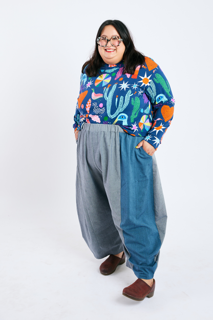 Person wearing a colorful patterned shirt and sustainable plus size barrel-leg pants on a white background