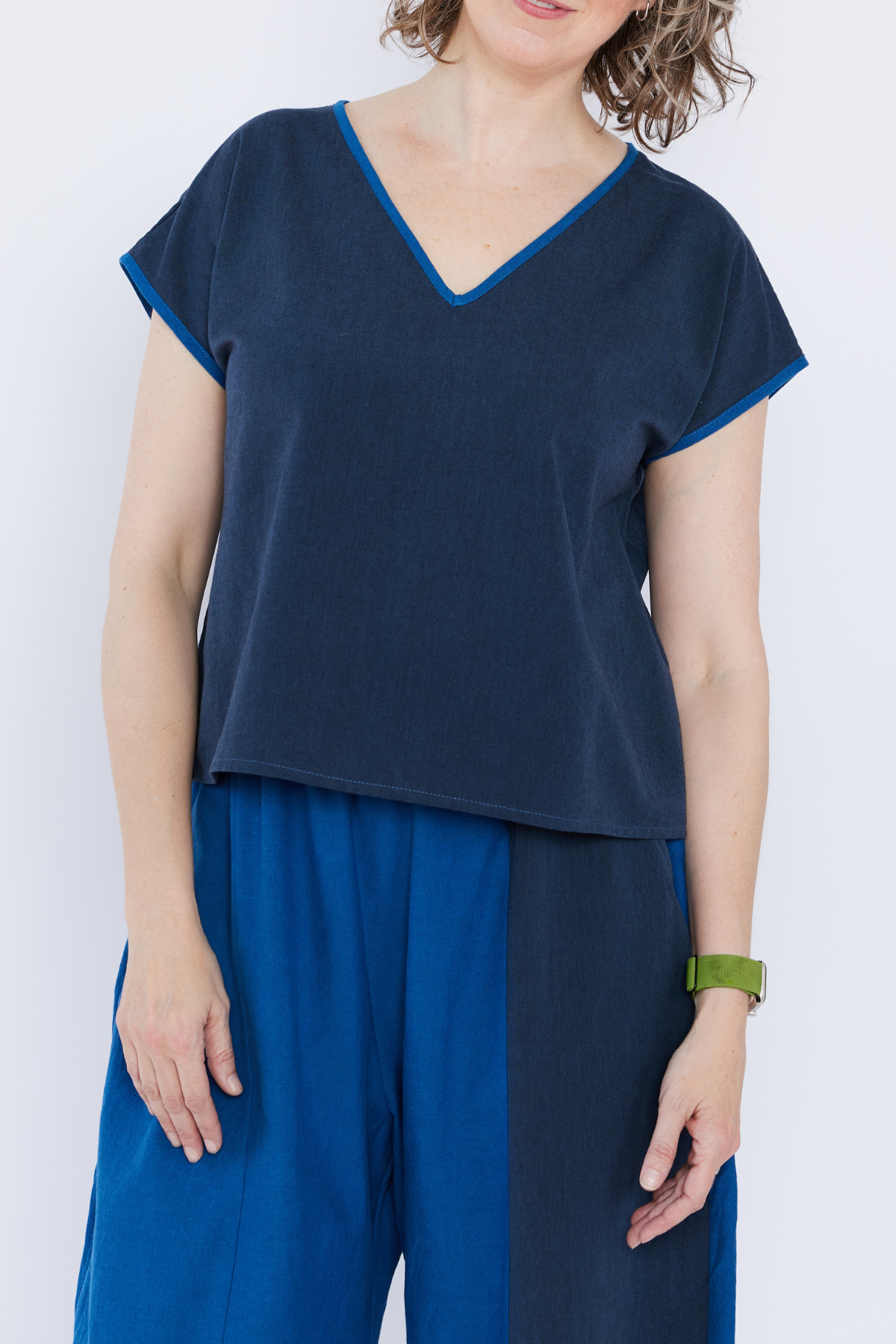 Woman wearing a navy blue top and blue pants against a white background