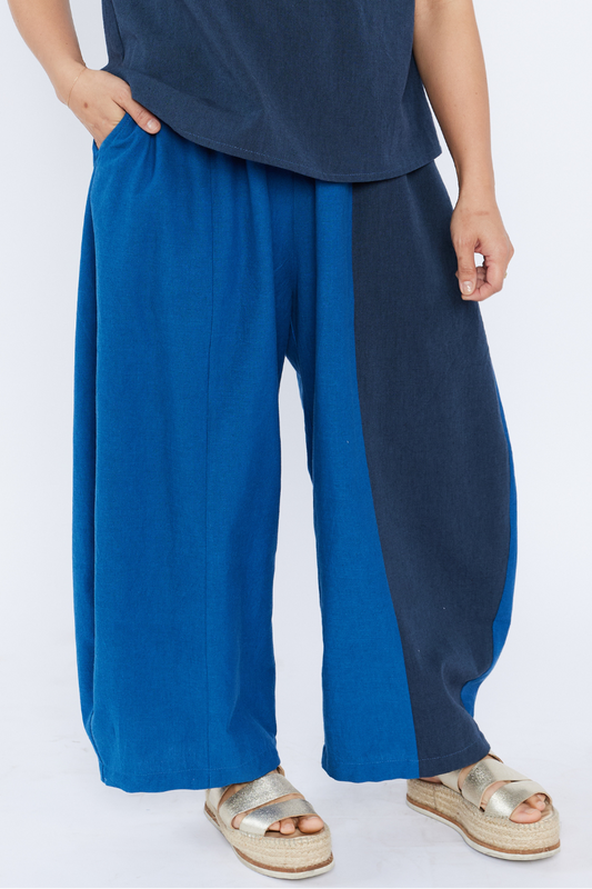 Woman wearing a blue cotton barrel pants with a plain background