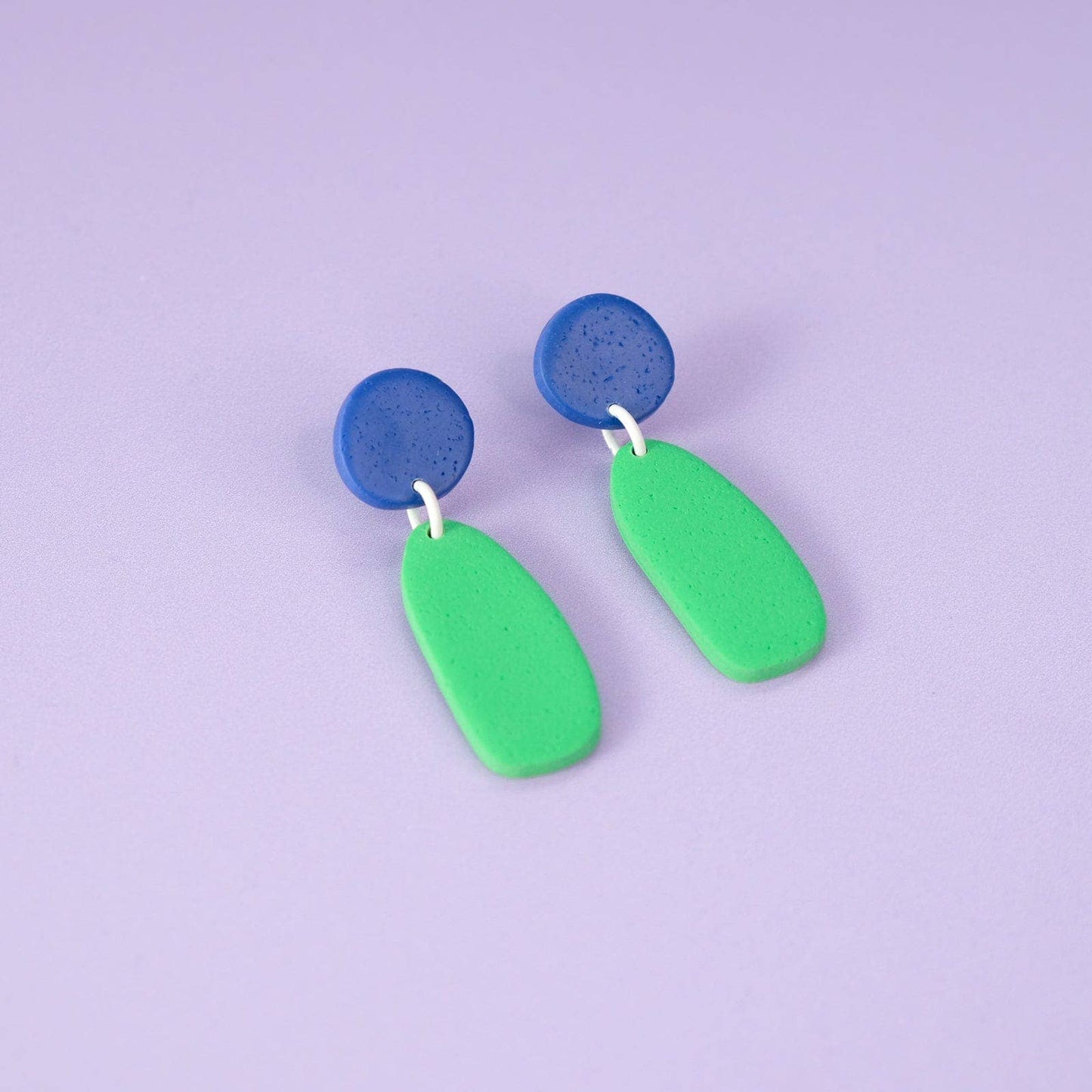 Lightweight statement earrings with blue and green shapes on a purple background