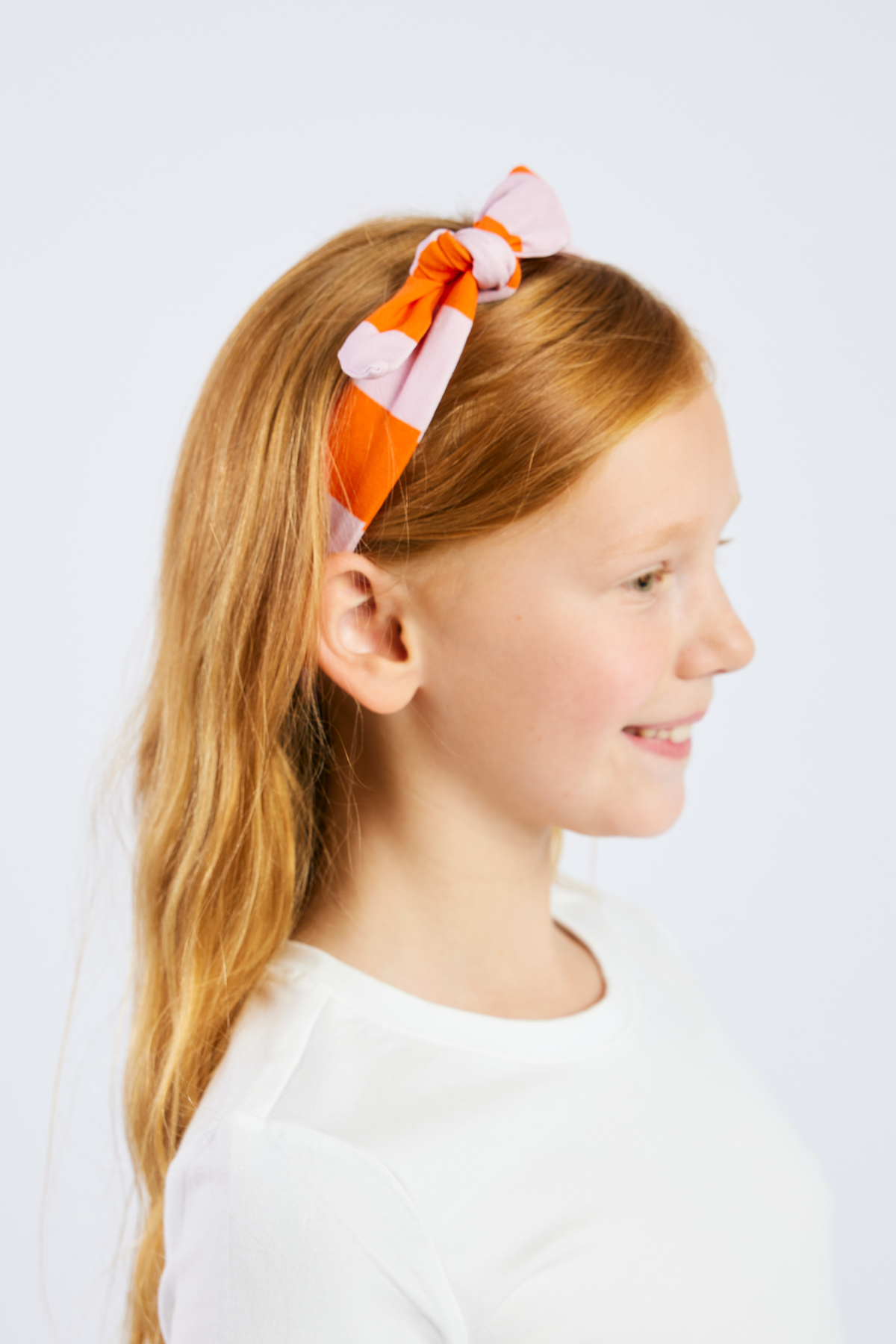 child wearing a pink and orange striped stretchy headband