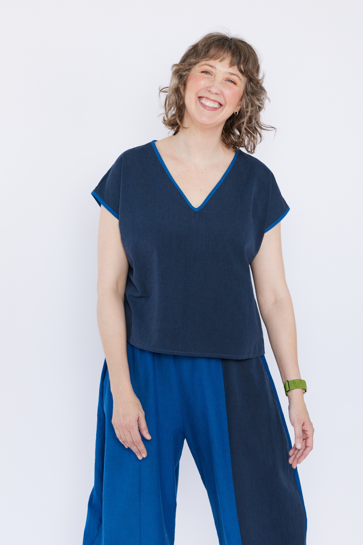 Woman wearing a blue top and pants against a white background