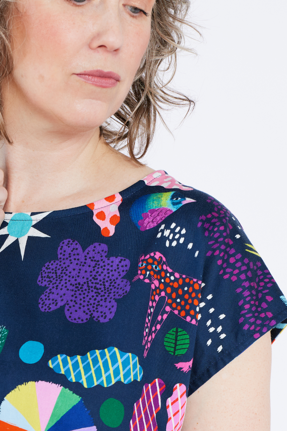 Person wearing a navy blue dress with colorful abstract patterns on a white background