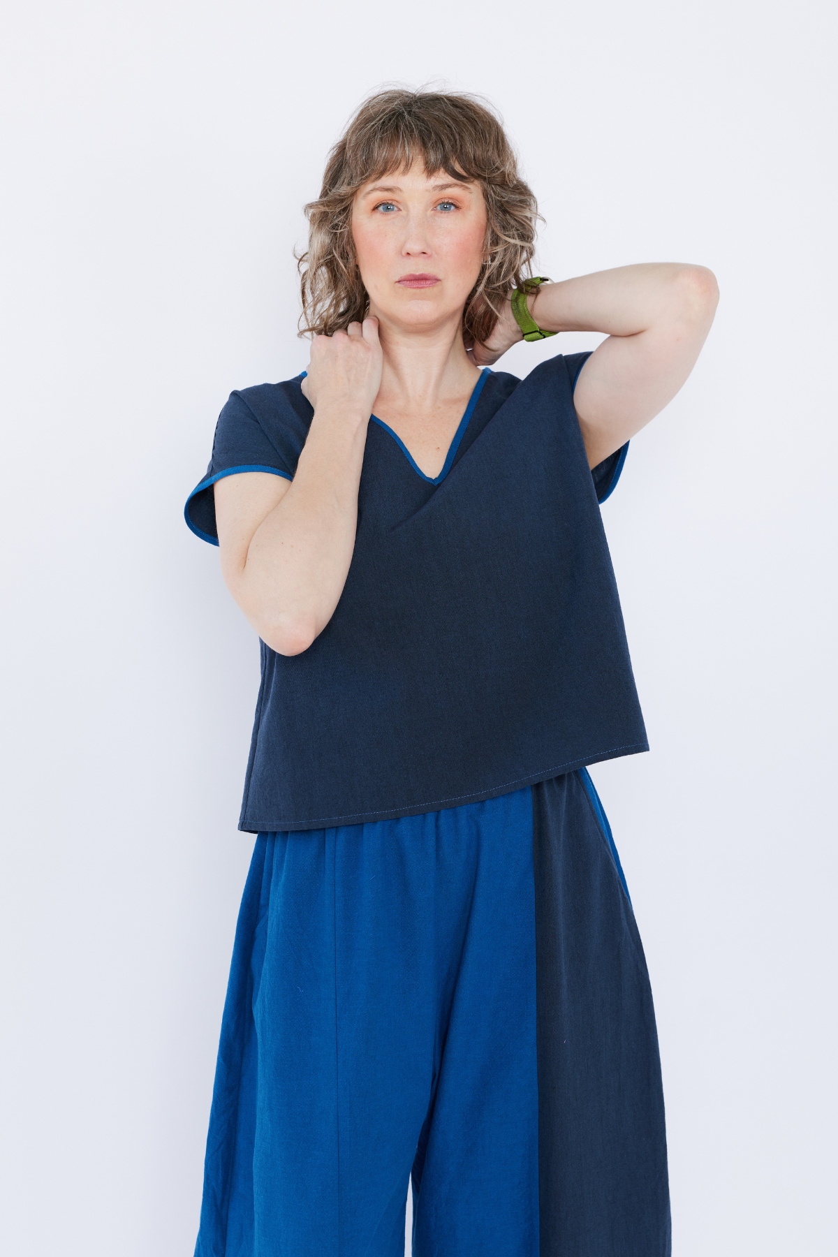Woman wearing a navy blue top and blue pants against a white background