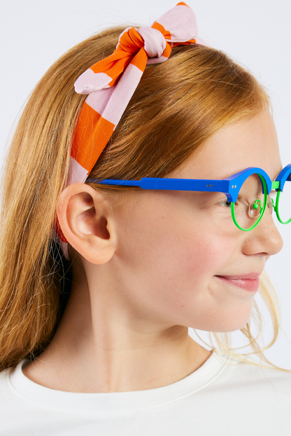 child wearing a pink and orange striped stretchy headband and bright blue glasses  from Eye Spy Optical