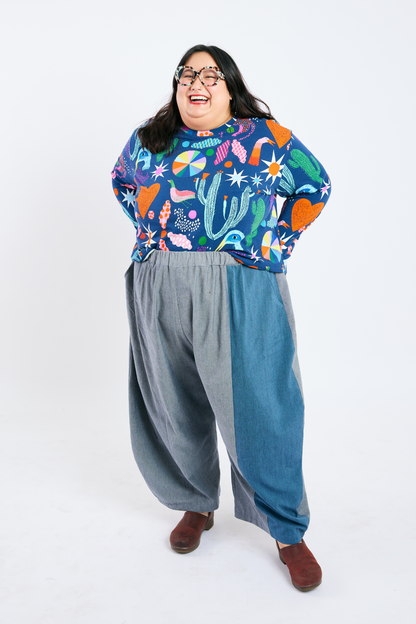 Person wearing a colorful plus size patterned top and plus size wide-leg pants on a white background