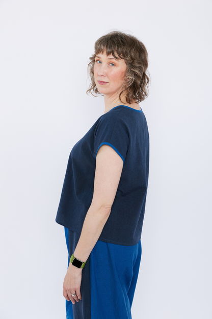 Woman wearing a navy blue top and blue pants against a white background