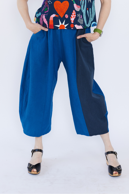 Person wearing blue wide-leg pants and a colorful top on a white background
