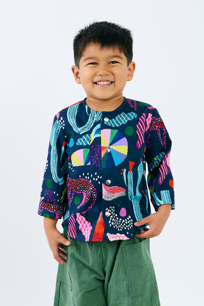 Child wearing a colorful patterned shirt with snaps with a plain background