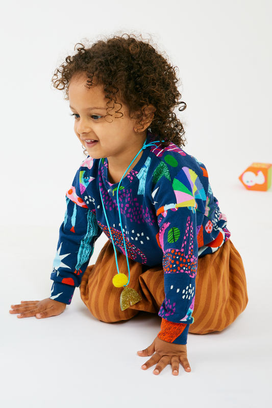 Child kneeling and wearing a Lilla Barn top and pants