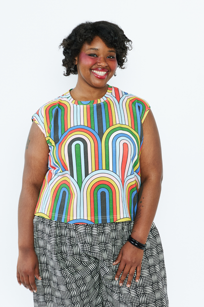 Person wearing a colorful sleeveless top with abstract patterns on a white background