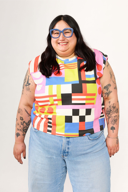 Person wearing a colorful checkered top and light blue jeans on a plain background