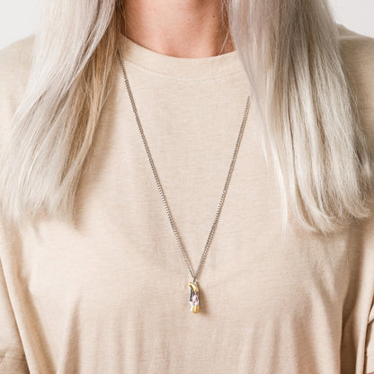 Necklace with a knife pendant worn by a person against a neutral background