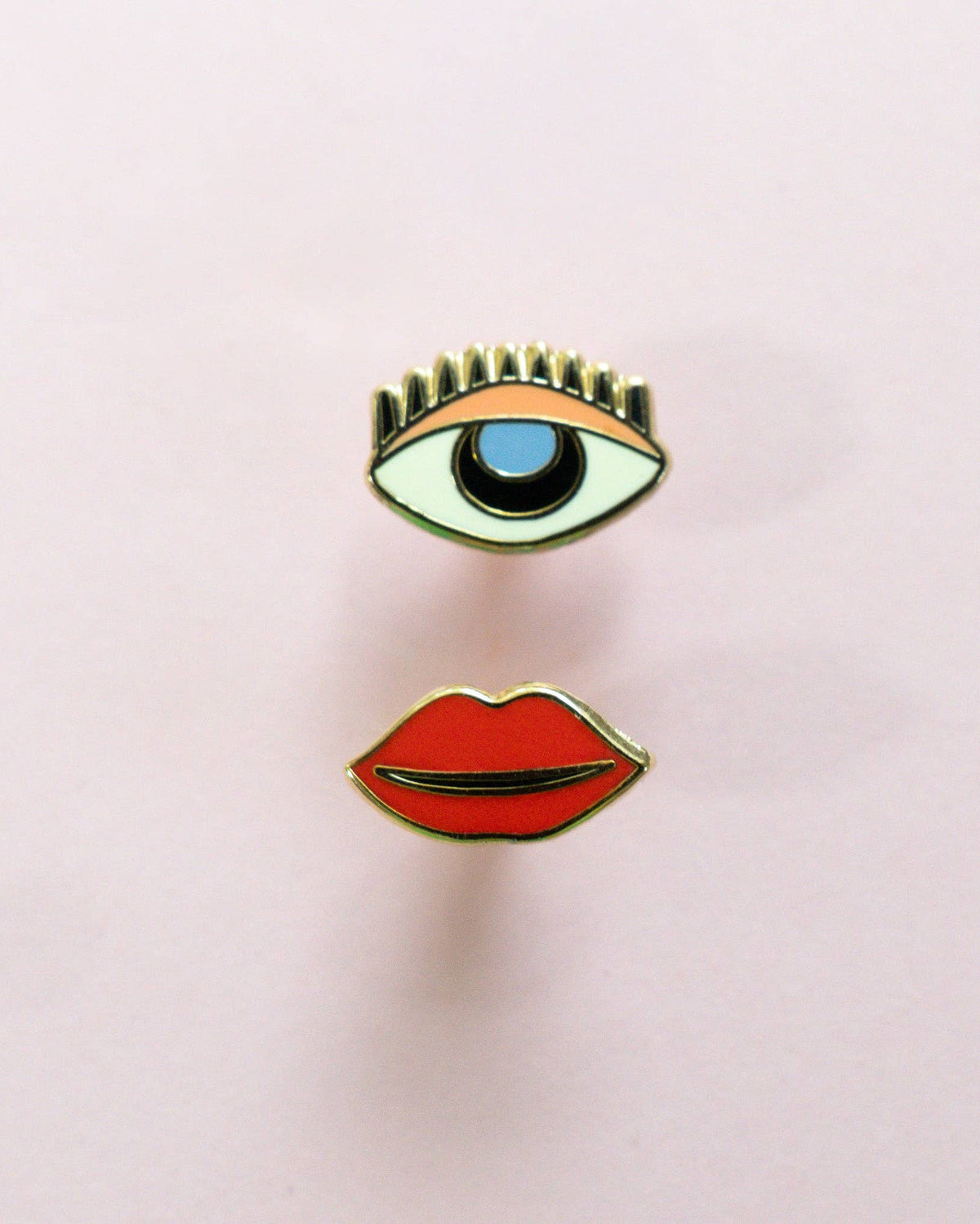 Mismatch stud earrings with one eye and one set of lips. sterling silver posts on a light pink background