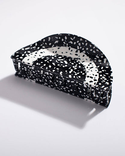 Black and white speckled hair clip on a light gray background