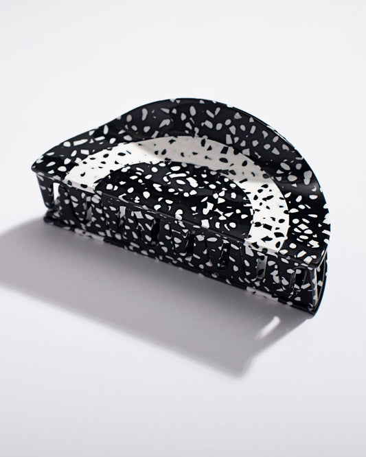 Black and white speckled hair clip on a light gray background