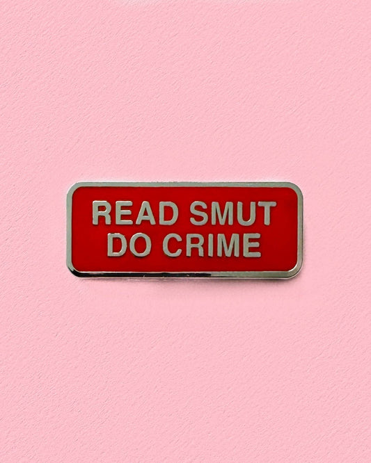 Red enamel pin with 'READ SMUT DO CRIME' text on a pink background