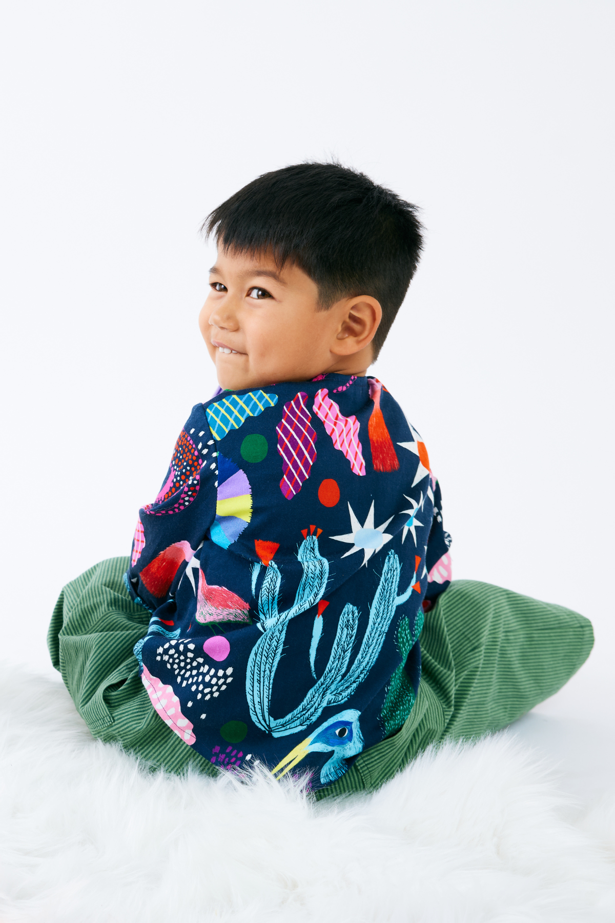 Child wearing a colorful outfit with a pattern of animals and plants on a white background