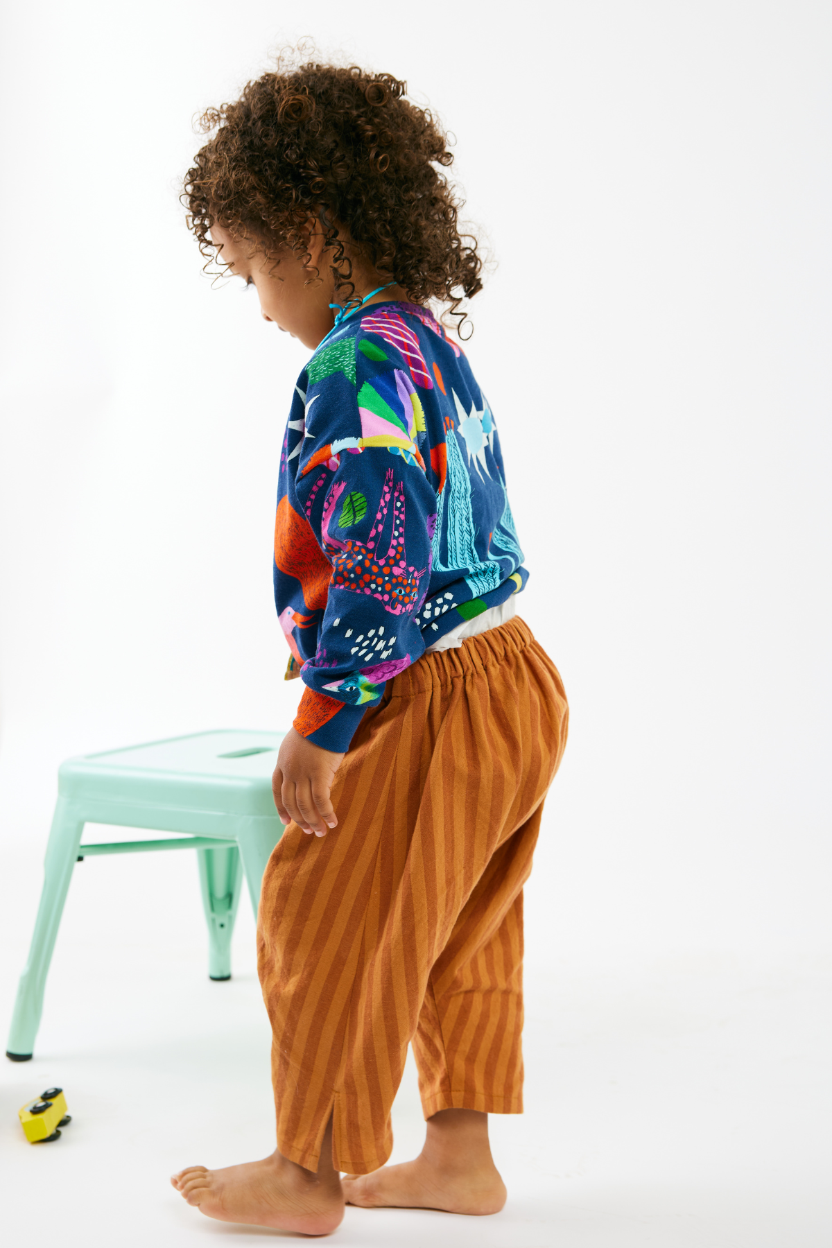 Child wearing a colorful kid top and striped pants by Lilla Barn Clothing