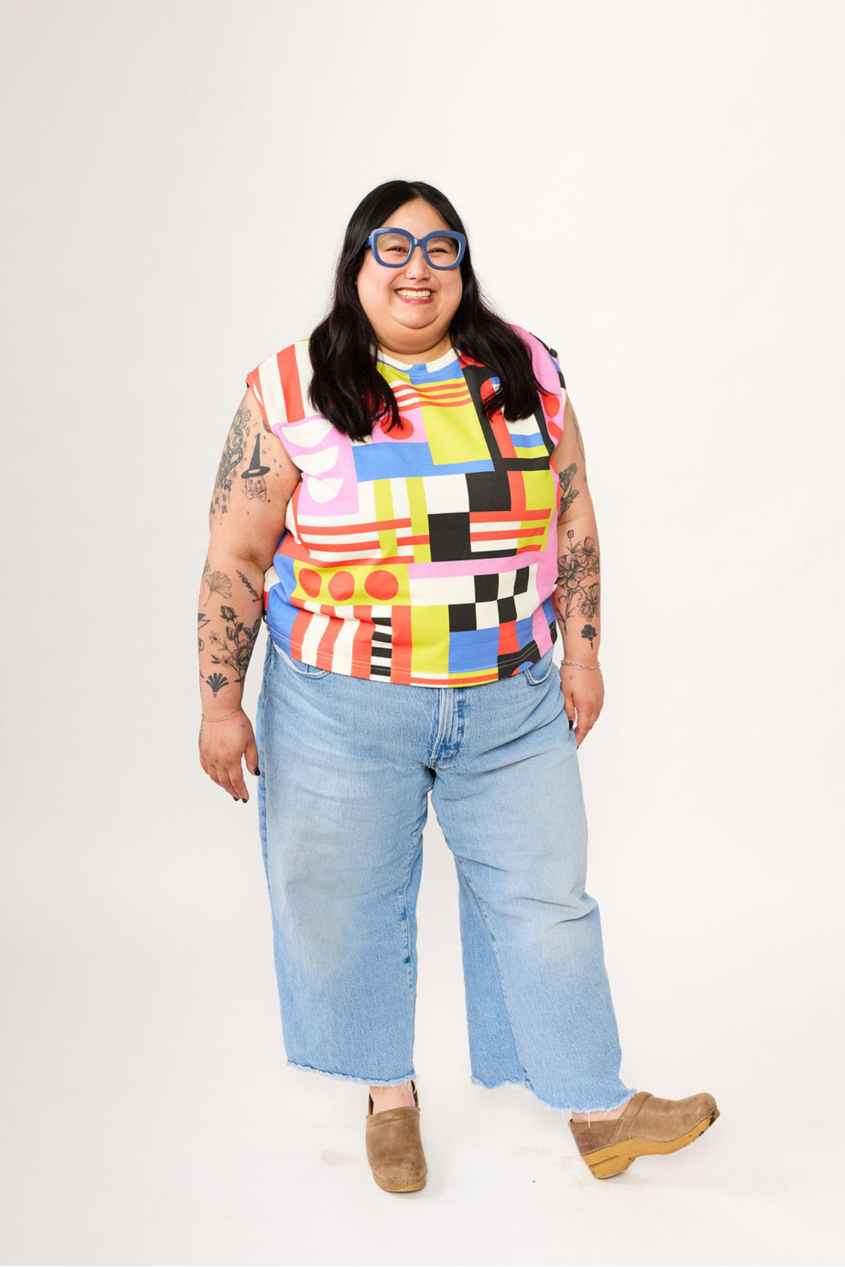 Person wearing a colorful patterned shirt and light blue jeans on a white background