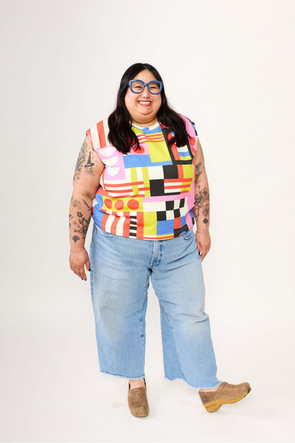 Person wearing a colorful patterned shirt and light blue jeans on a white background